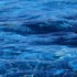 Niebieska tafla wody z widocznymi falami i refleksami światła