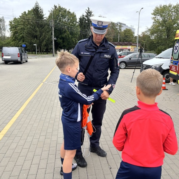Policjant rozdaje dzieciom elementy odblaskowe podczas akcji bezpieczeństwa w Białej Podlaskiej